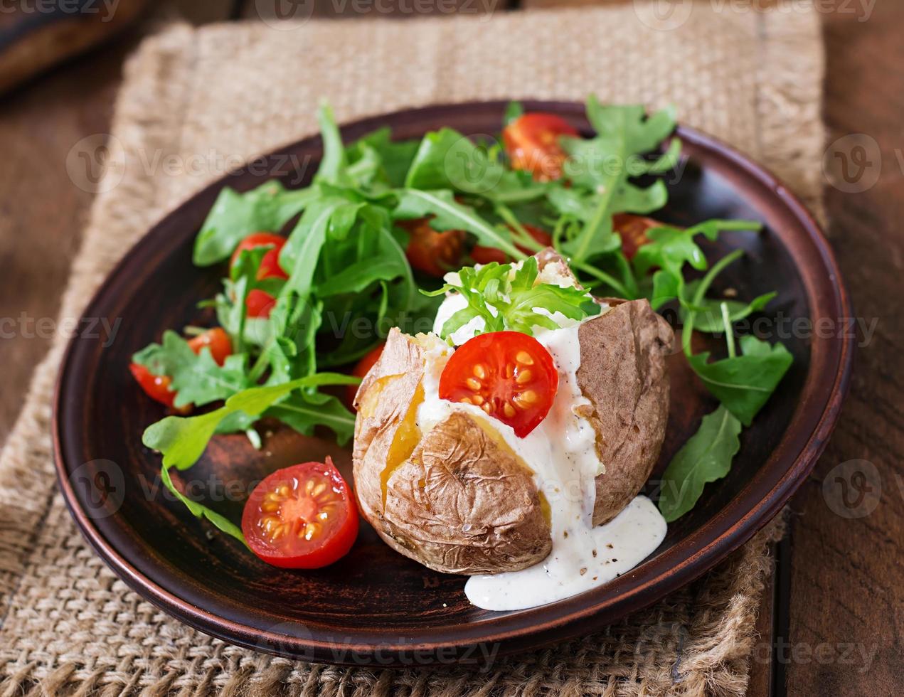 Baked potato filled with sour cream, arugula and tomatoes photo