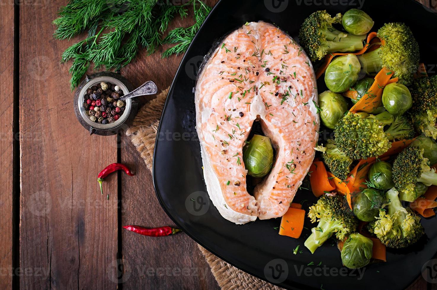 Cooked on steam salmon steak with vegetables. Top view photo