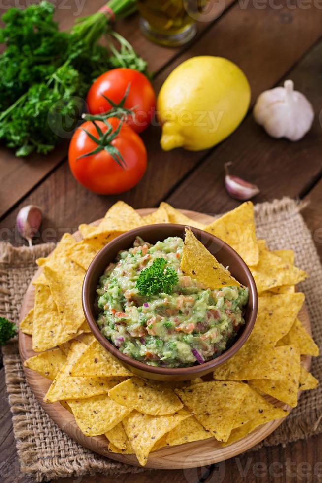 aguacate guacamole, lima, tomate, cebolla y cilantro, servido con nachos - merienda tradicional mexicana foto