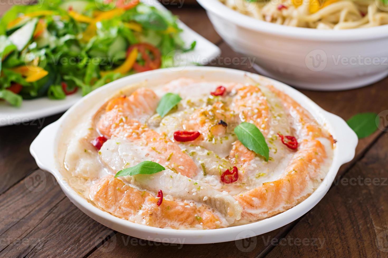 Baked slices of red and white fish with honey and lime juice, served with fresh salad and soft noodles in miso broth photo
