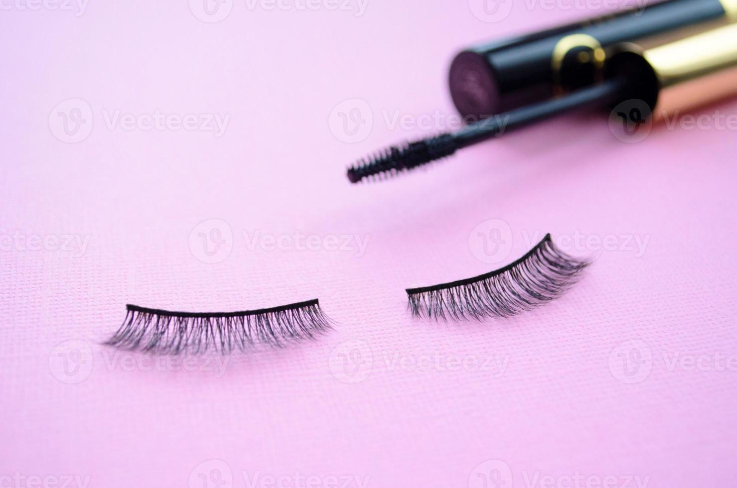 false eye lashes and black mascara on a purple background. Mascara or false lashes photo