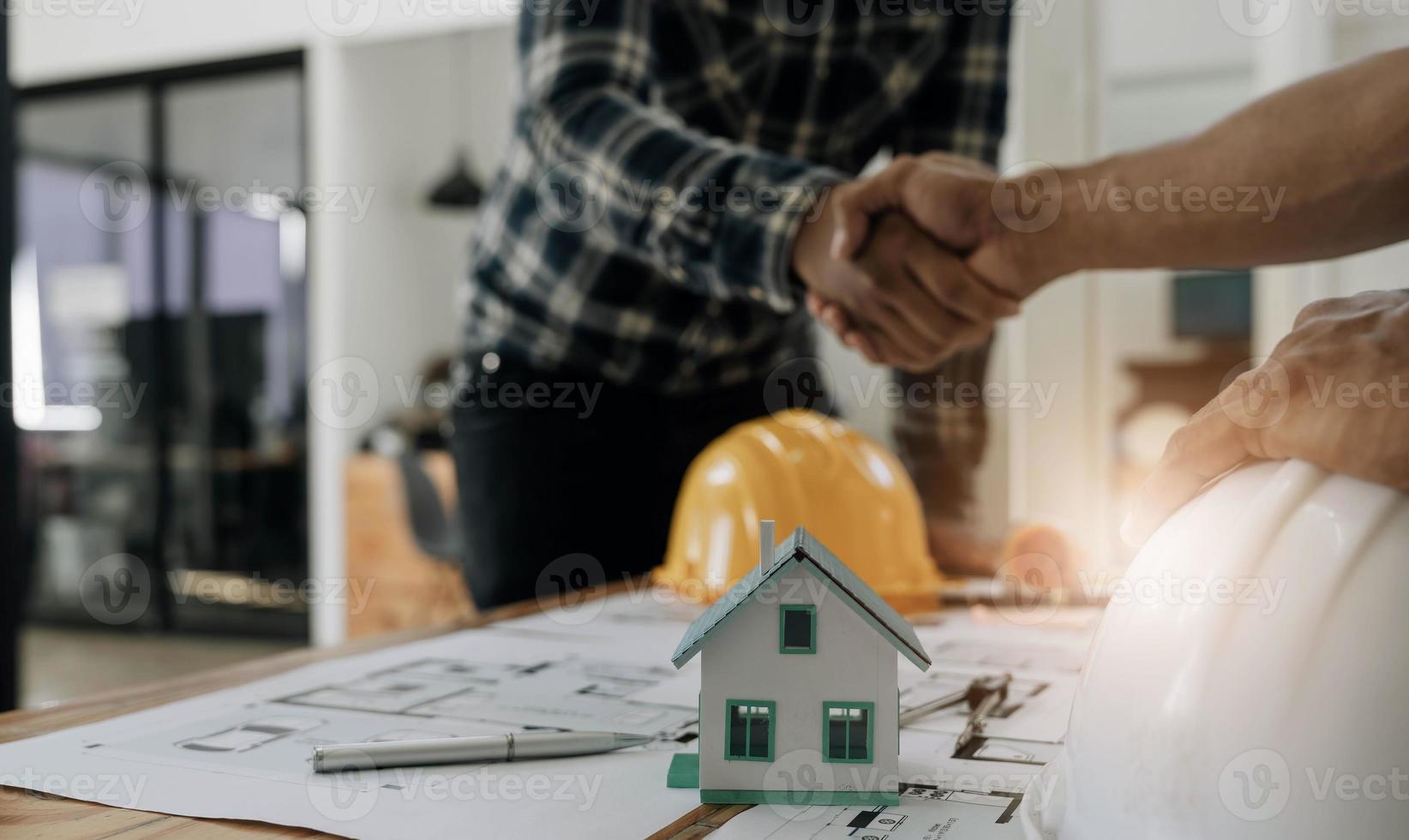 ingenieros o arquitectura estrechando la mano en el sitio de construcción para el proyecto arquitectónico, sosteniendo casco de seguridad en sus manos. foto