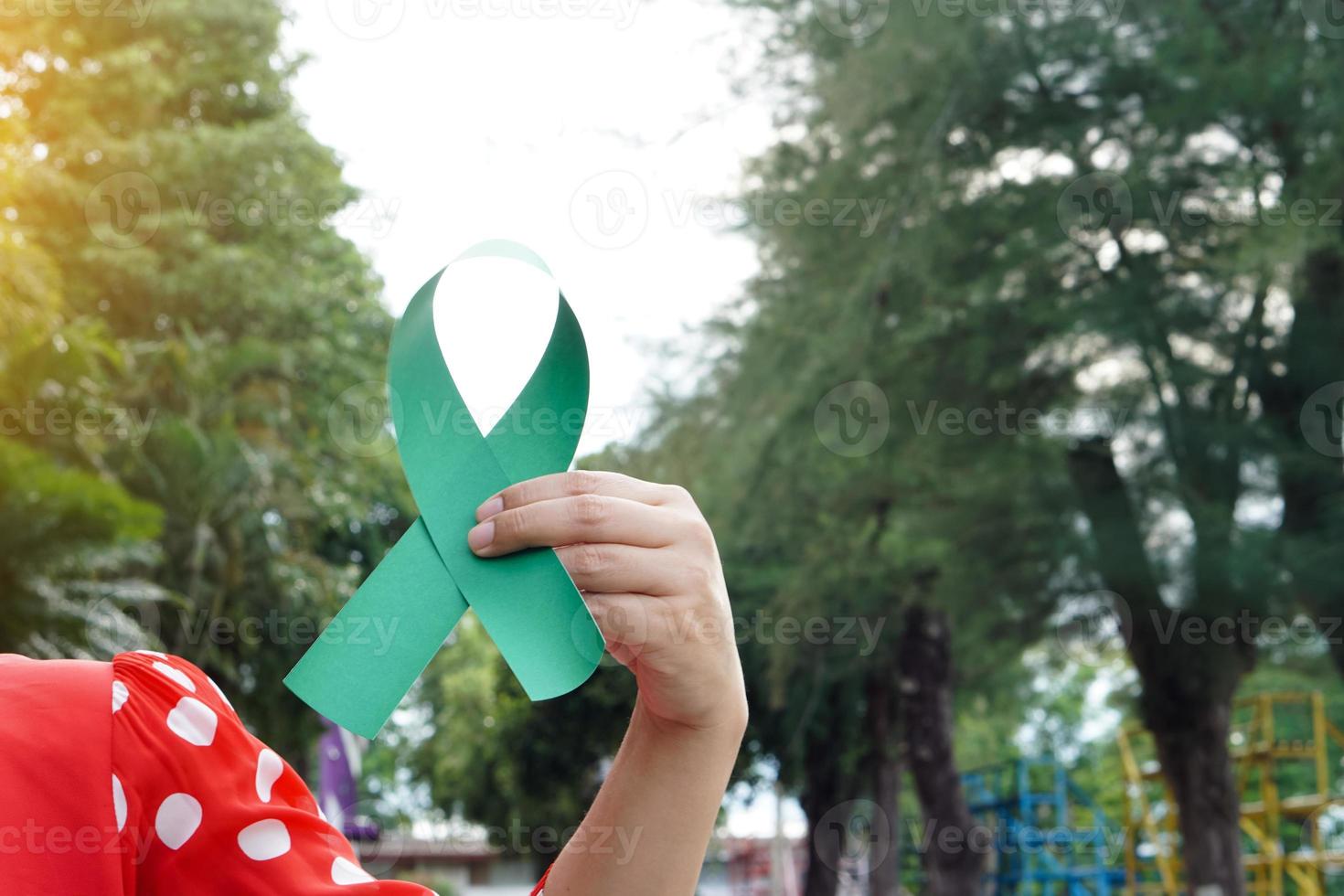 la mano sostiene la cinta de conciencia verde. concepto , linfoma , cáncer de hígado y sensibilización sobre la salud mental apoyo y ayuda a los pacientes que viven con enfermedades en todo el mundo. octubre mes de concientización sobre el cáncer. foto