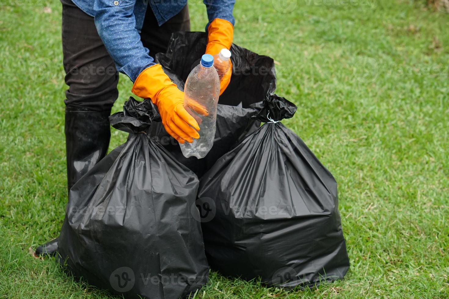 Closeup garbage collector worker hands hold plastic bottles to put into black garbage bags to recycle. Concept , Waste management. Environment problems. Daily chores. Throw away rubbish . photo