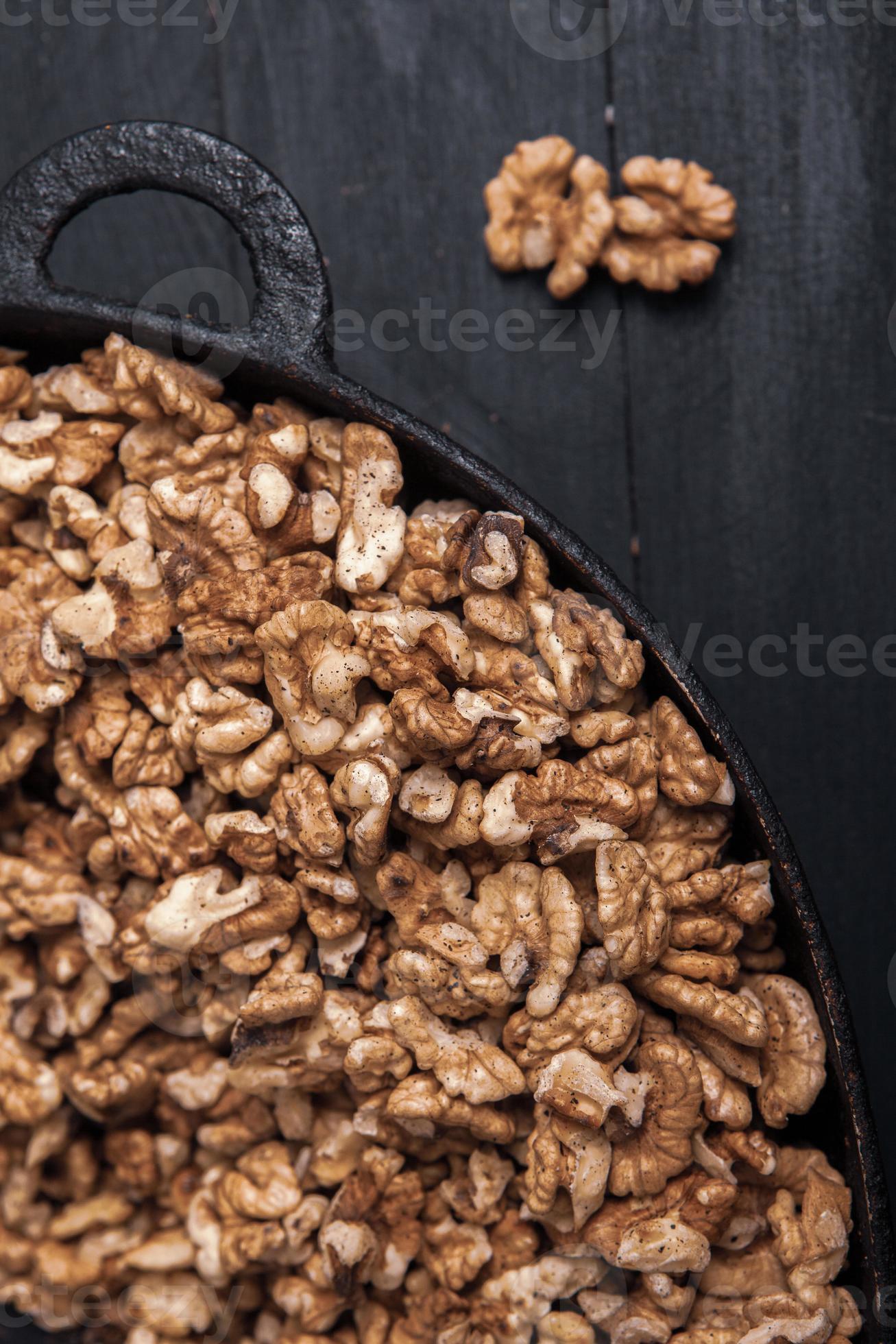Walnut background. Peeled walnuts on a iron plate on black. walnuts a real super food full of