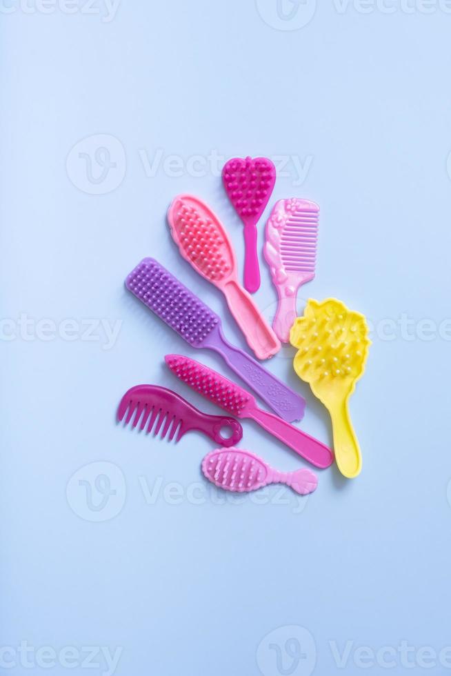 Hair care is a creative concept. Colored doll combs on a blue background. Copy space photo