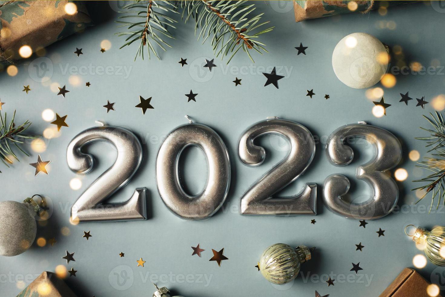 Numbers of year 2023 made by candles. Fir tree, gift box, holiday decoration on blue background. Christmas postcard. Happy New Year 2023 card concept photo