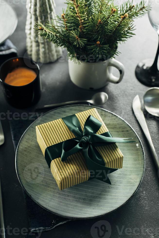 Christmas or New Year Table Setting. Craft blue plate with cutlery and gift box, fir tree branches photo