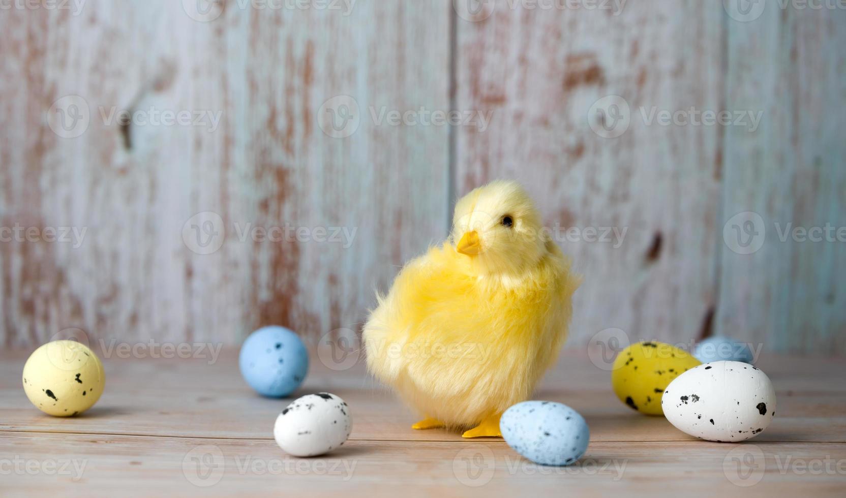 tarjeta de felicitación de pascua con pollo cpequeño rodeado de huevos coloridos sobre fondo azul foto