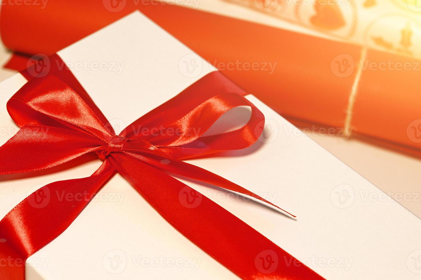 Gift with red bow and wrapping paper near.Christmas concept photo