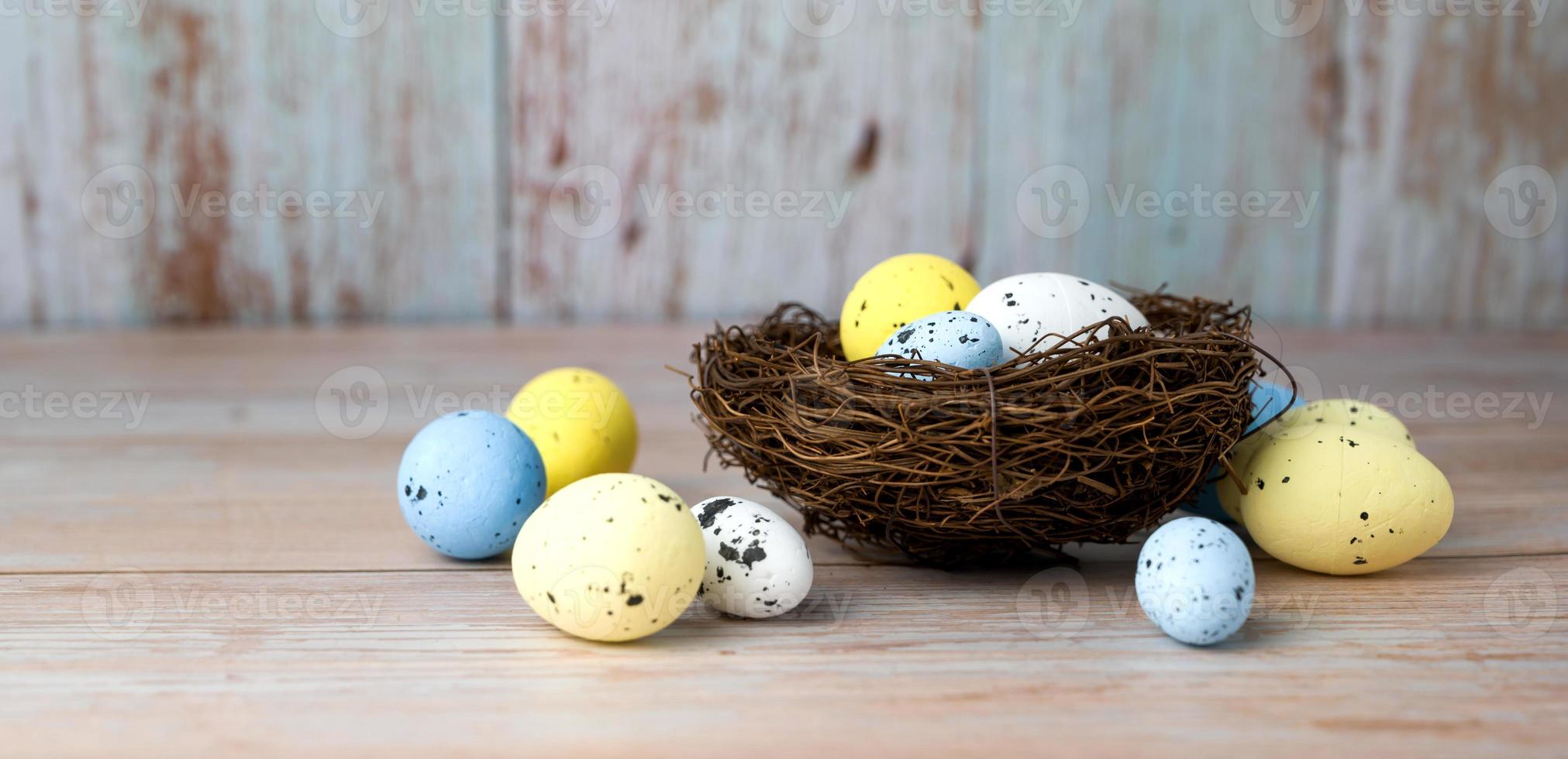Nest filled with white,yellow and blue eggs. Happy easter banner with place for text photo