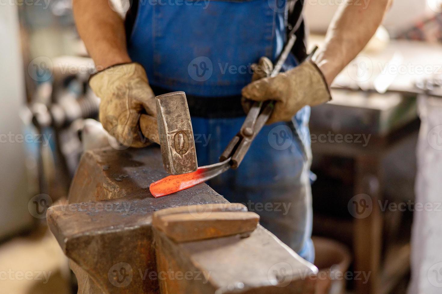 Close up view of heated metal and anvil. The blacksmith in the production process of metal products handmade in the forge. Blacksmith forging metal with a hammer. Metal industry, old profession. photo