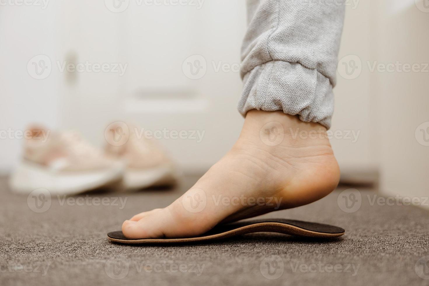 Flat feet diagnosis and orthotics, shoe inserts. Problems with flatfoot, pain. Identification of flat foot. Treatment to plantar fasciitis. Womans foot and insoles at home, close up view. photo