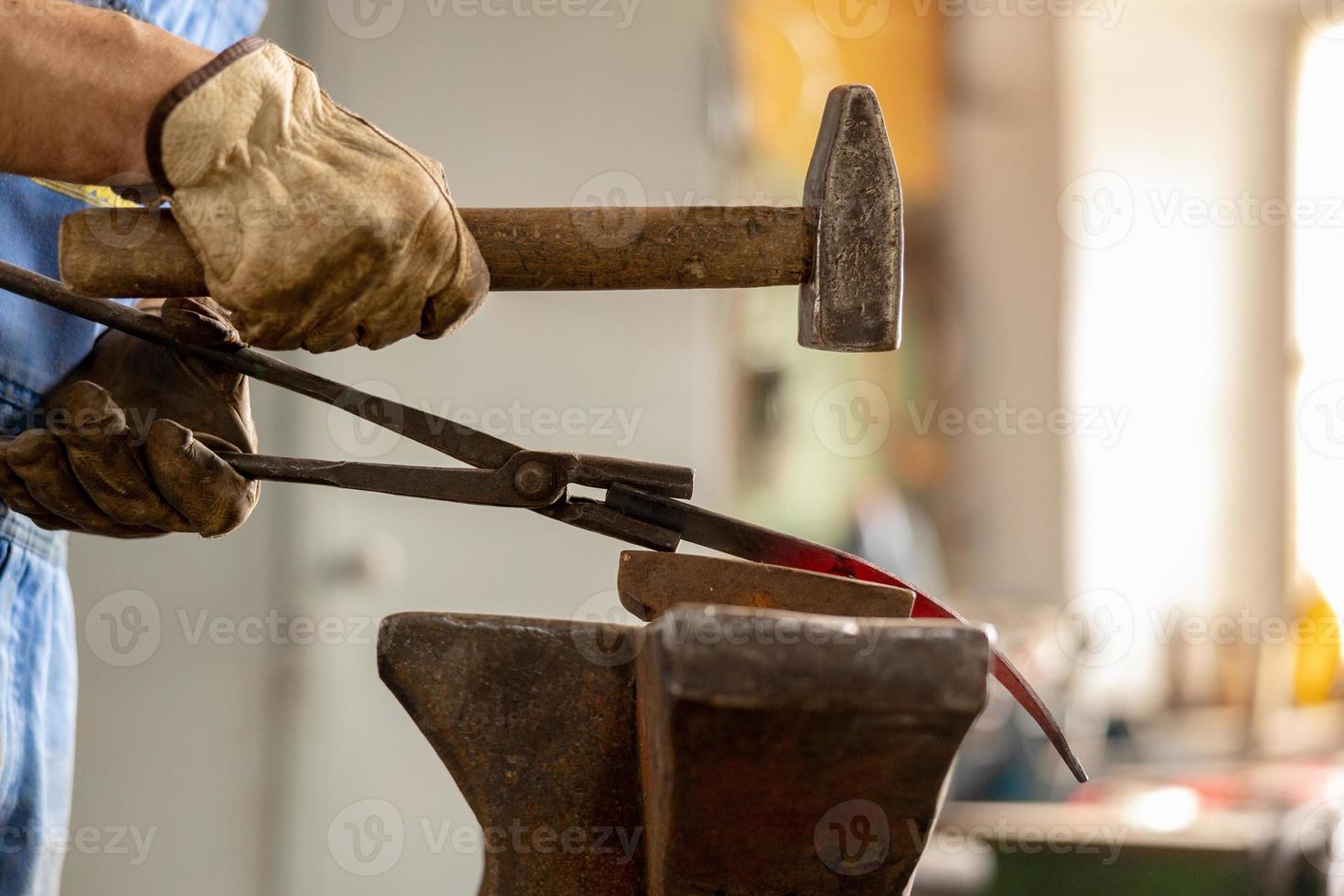 vista de cerca del metal calentado y el yunque. el herrero en el proceso de producción de productos metálicos hechos a mano en la fragua. herrero forjando metal con un martillo. industria metalúrgica, antigua profesión. foto