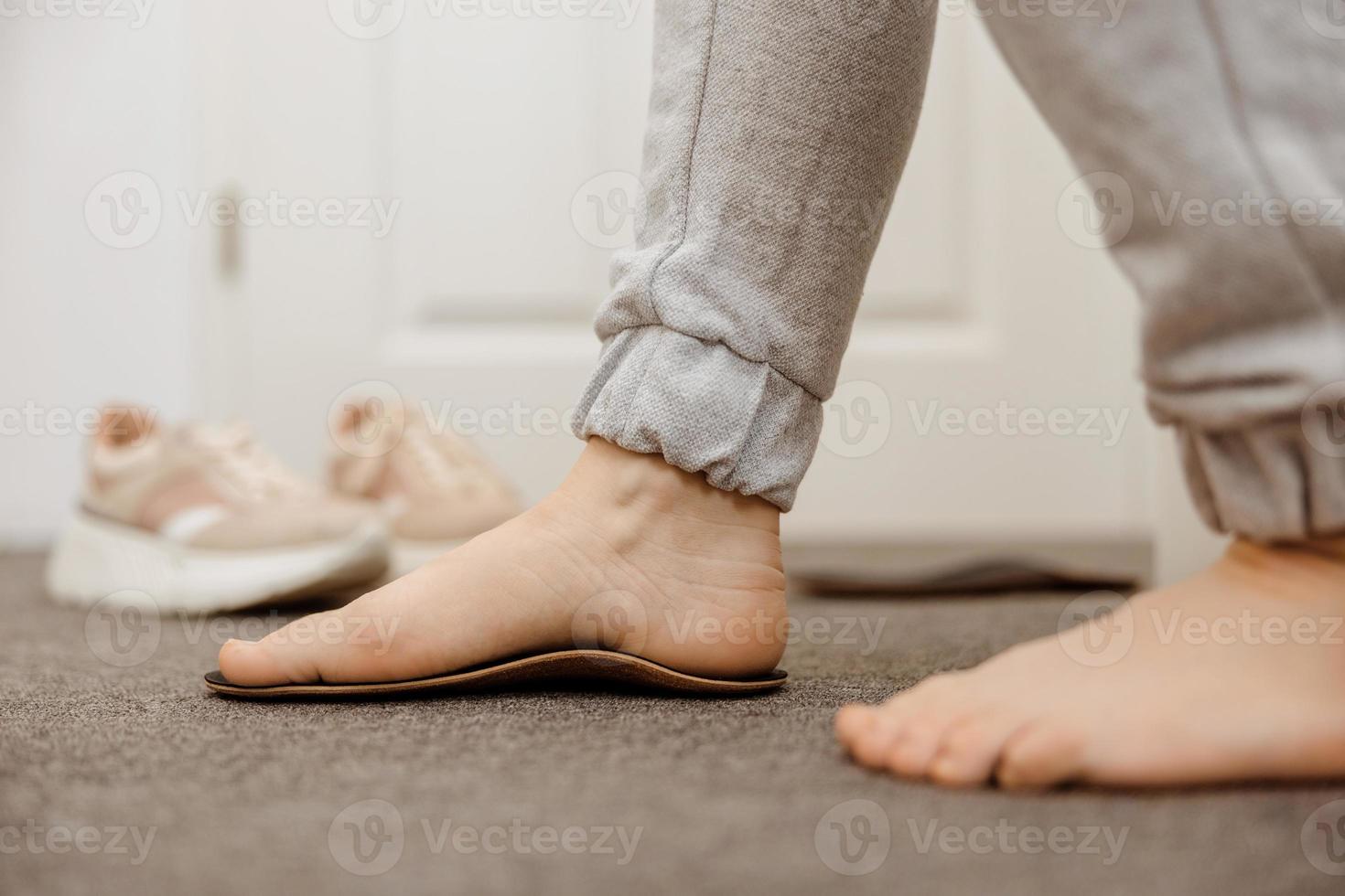 Flat feet diagnosis and orthotics, shoe inserts. Problems with flatfoot, pain. Identification of flat foot. Treatment to plantar fasciitis. Womans foot and insoles at home, close up view. photo