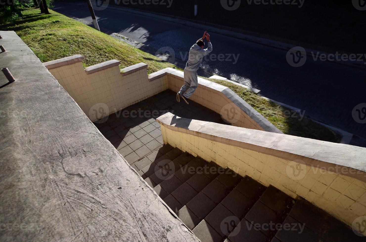 A young guy performs a jump through the space between the concrete parapets. The athlete practices parkour, training in street conditions. The concept of sports subcultures among youth photo