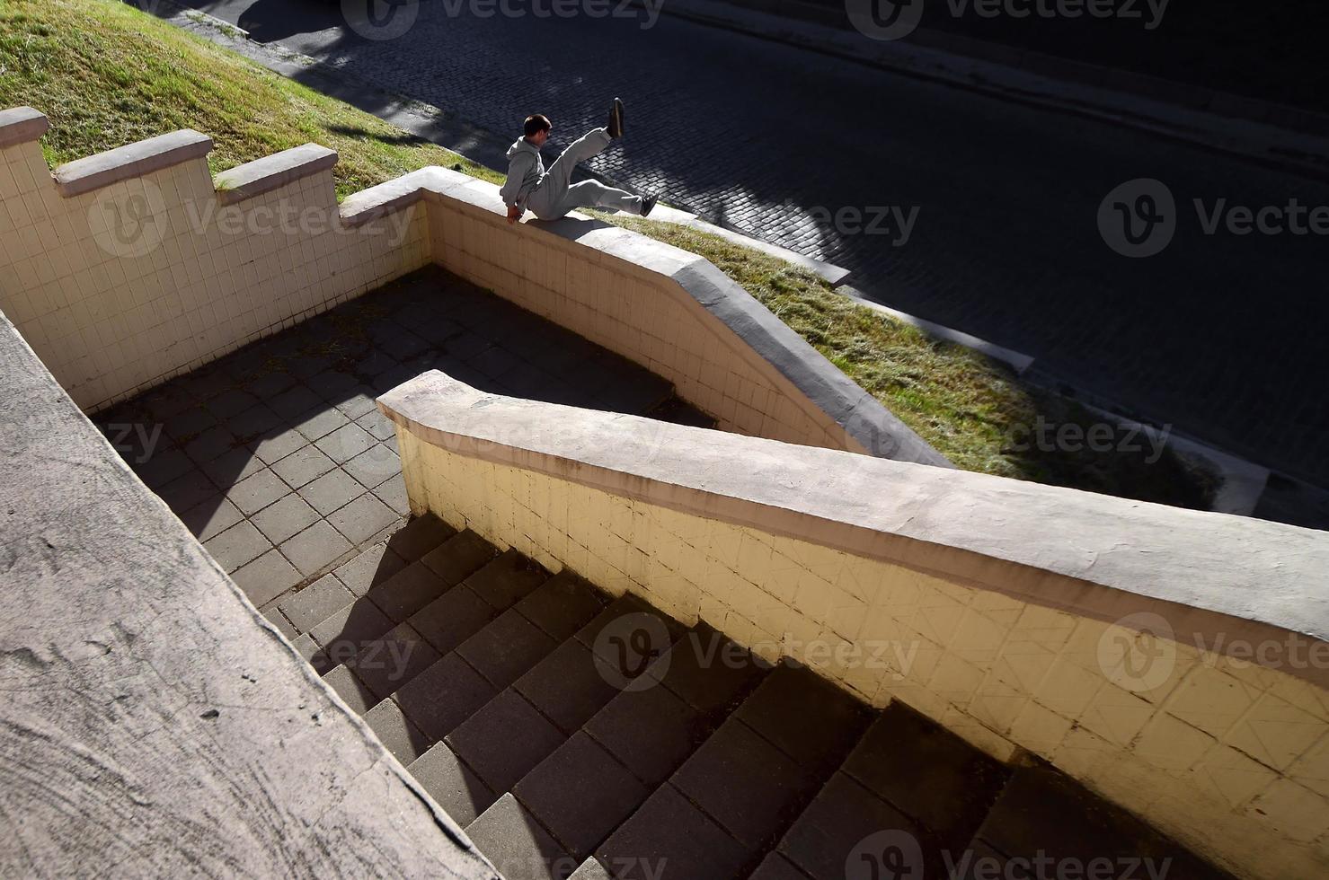 un joven realiza un salto a través del parapeto de hormigón. el atleta practica parkour, entrenando en condiciones de calle. el concepto de subculturas deportivas entre los jóvenes foto