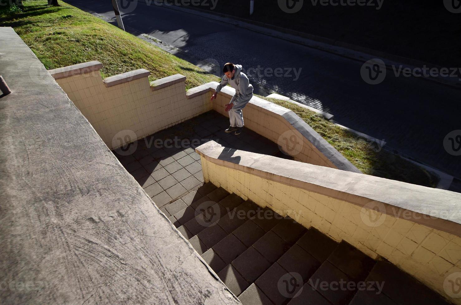 A young guy performs a jump through the space between the concrete parapets. The athlete practices parkour, training in street conditions. The concept of sports subcultures among youth photo