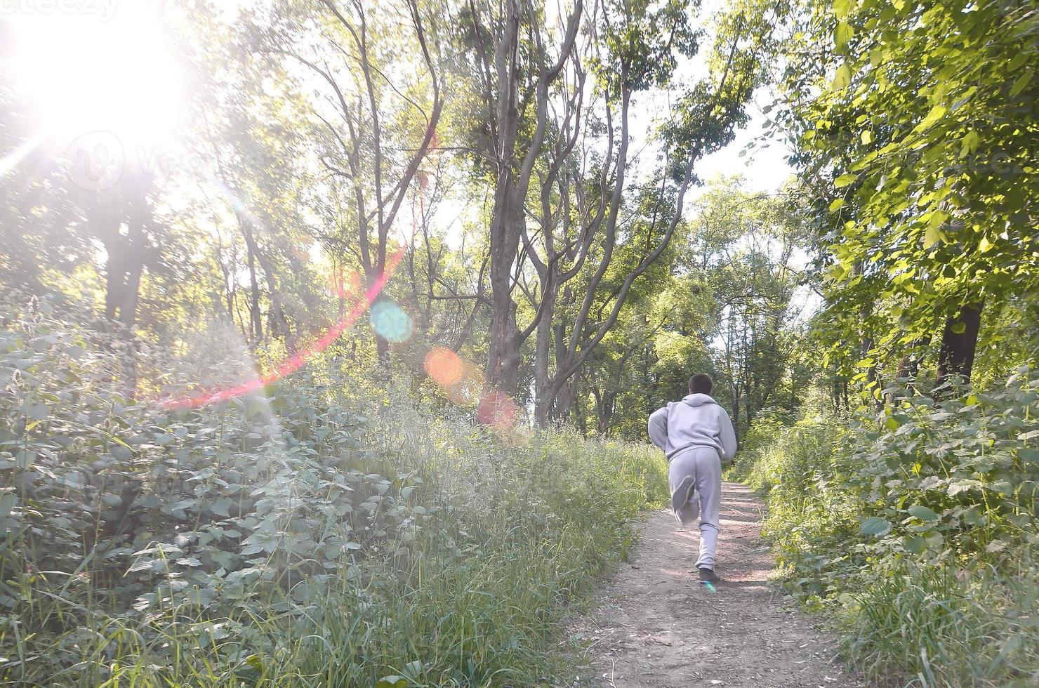 un joven con un traje deportivo gris corre por el camino entre los foto