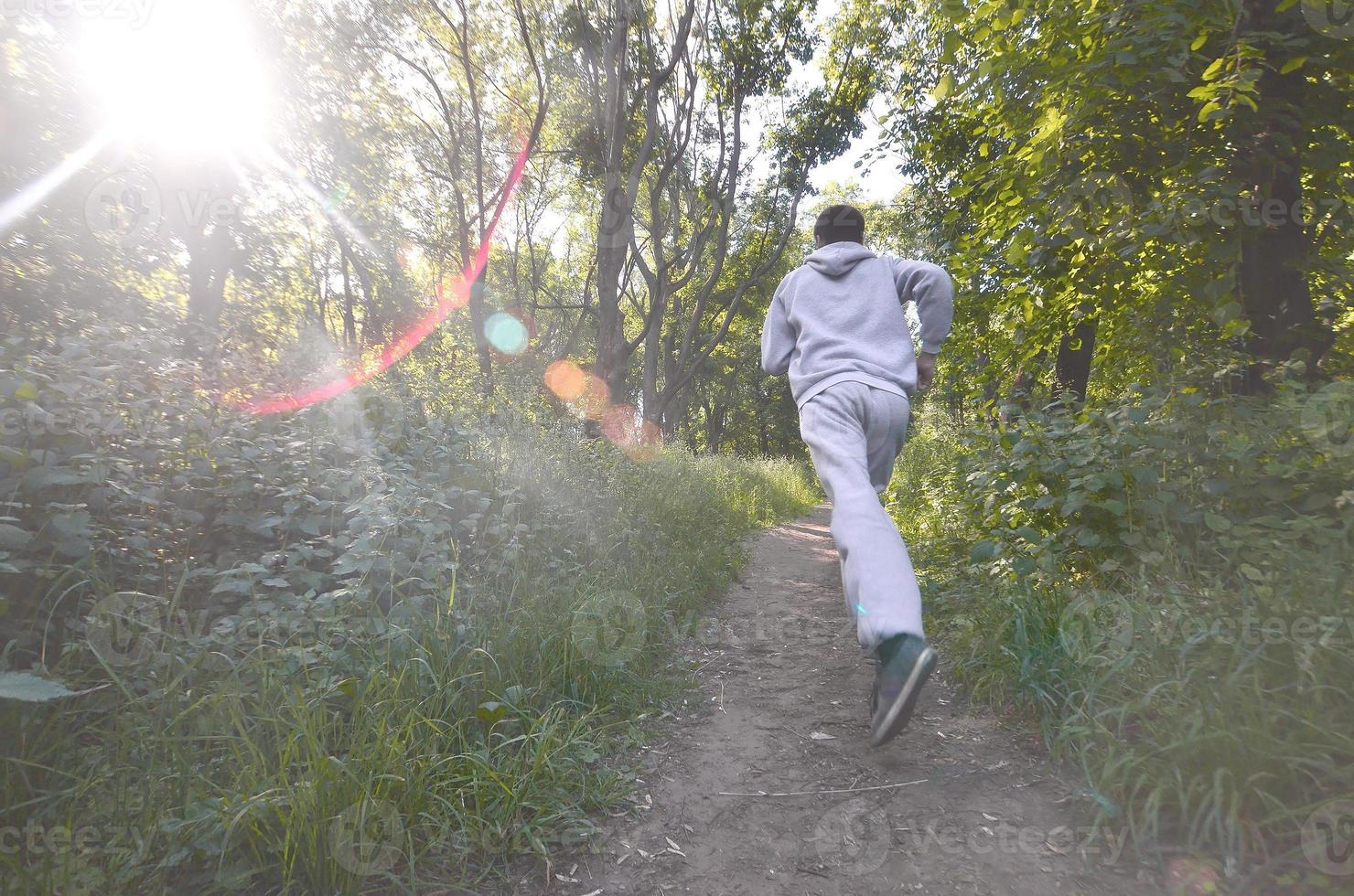 un joven con un traje deportivo gris corre por el camino entre los foto