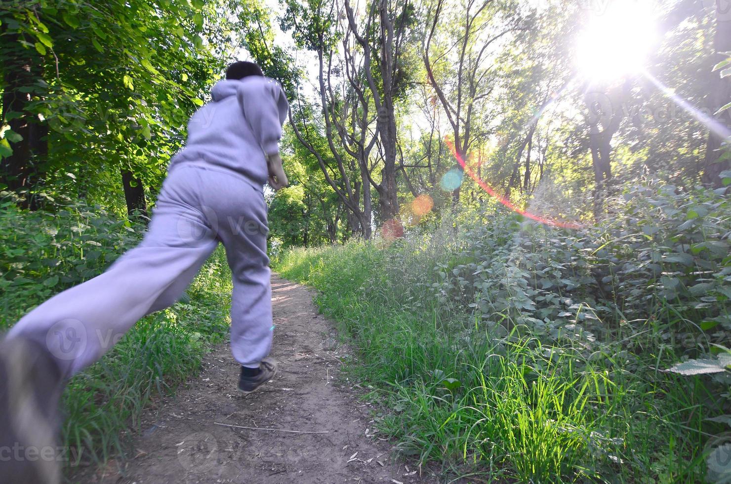 A young guy in a gray sports suit runs along the path among the photo