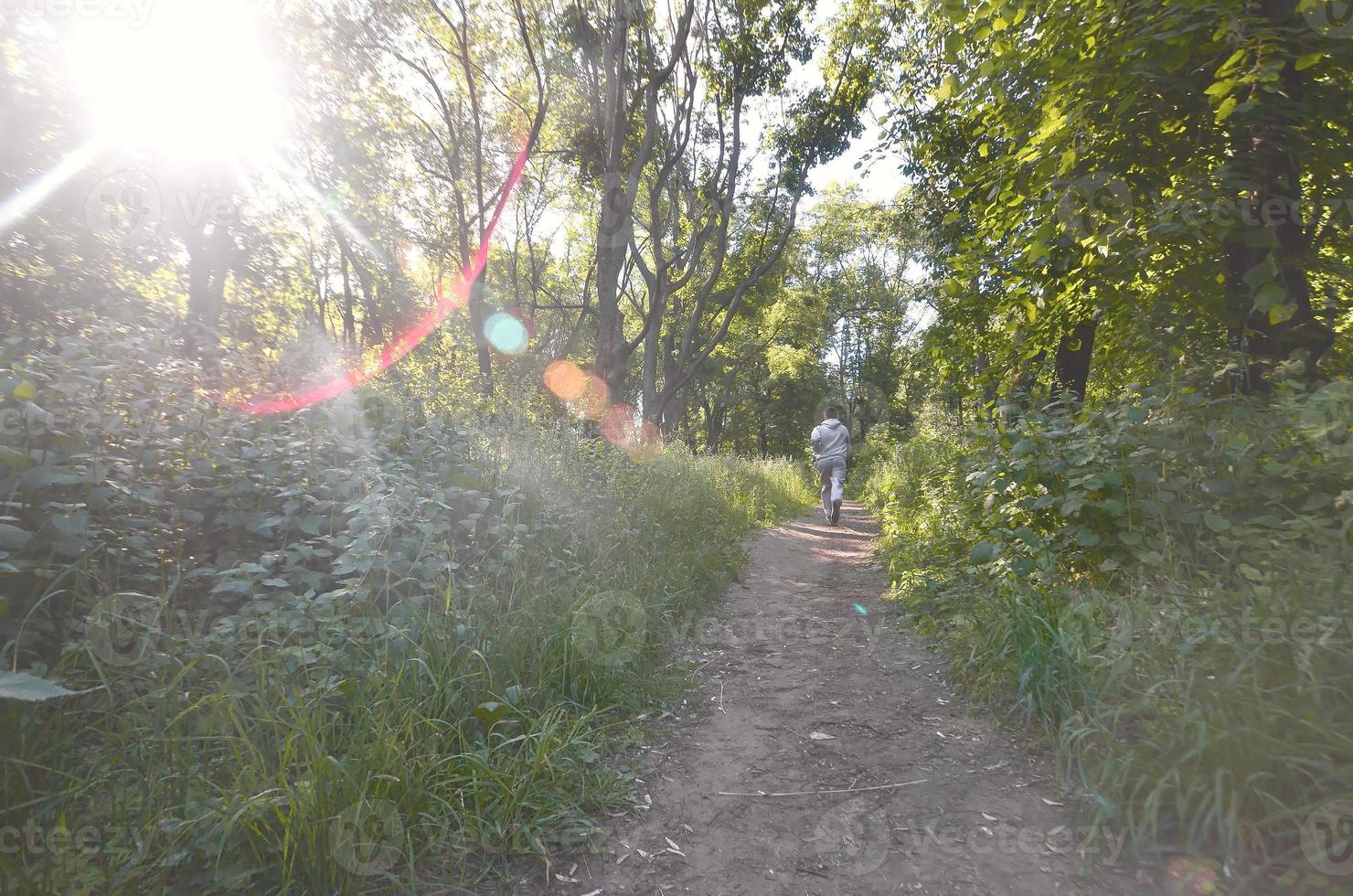 un joven con un traje deportivo gris corre por el camino entre los foto