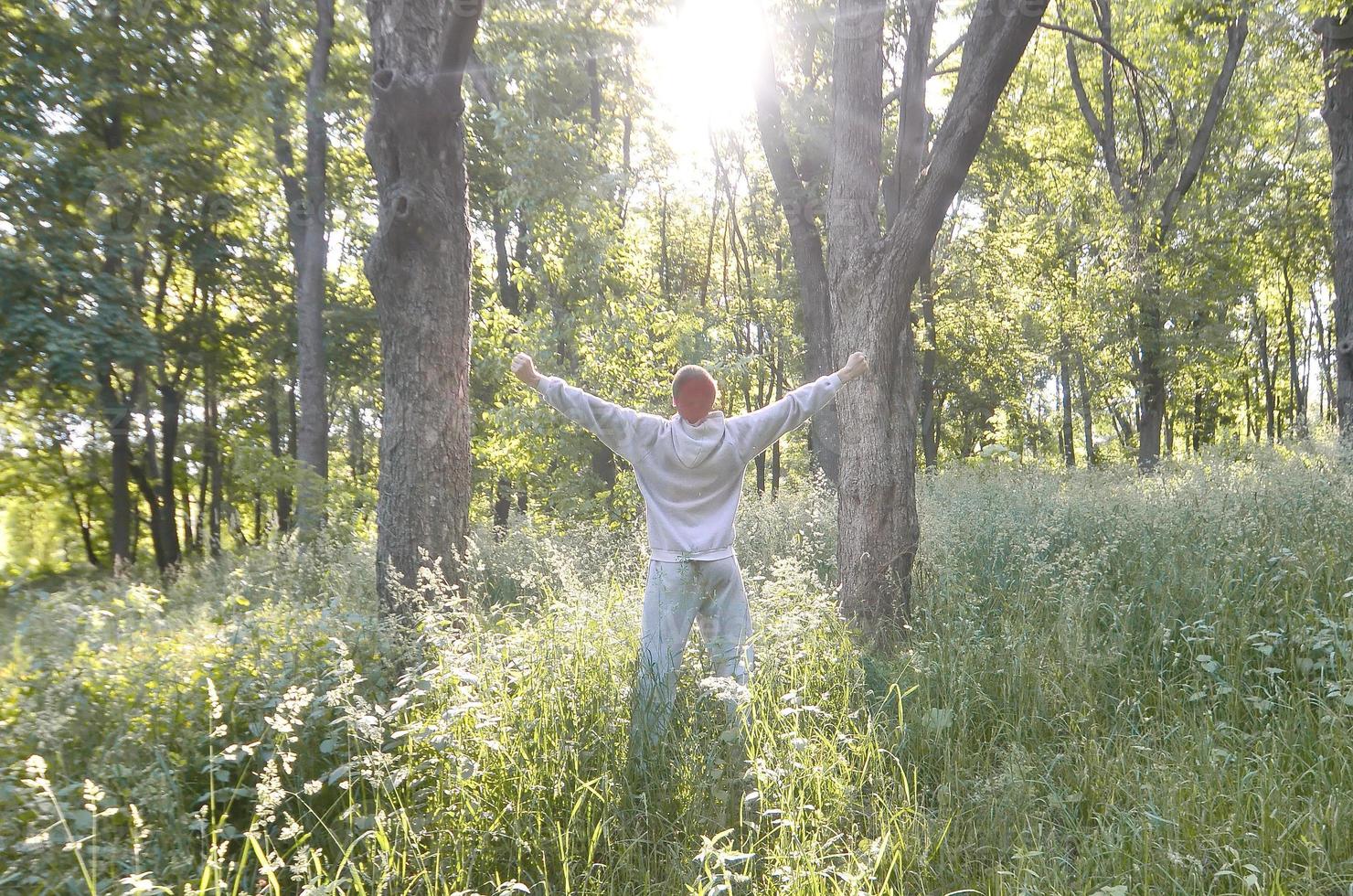 A young guy in a gray sports suit rejoices in the rising of the photo