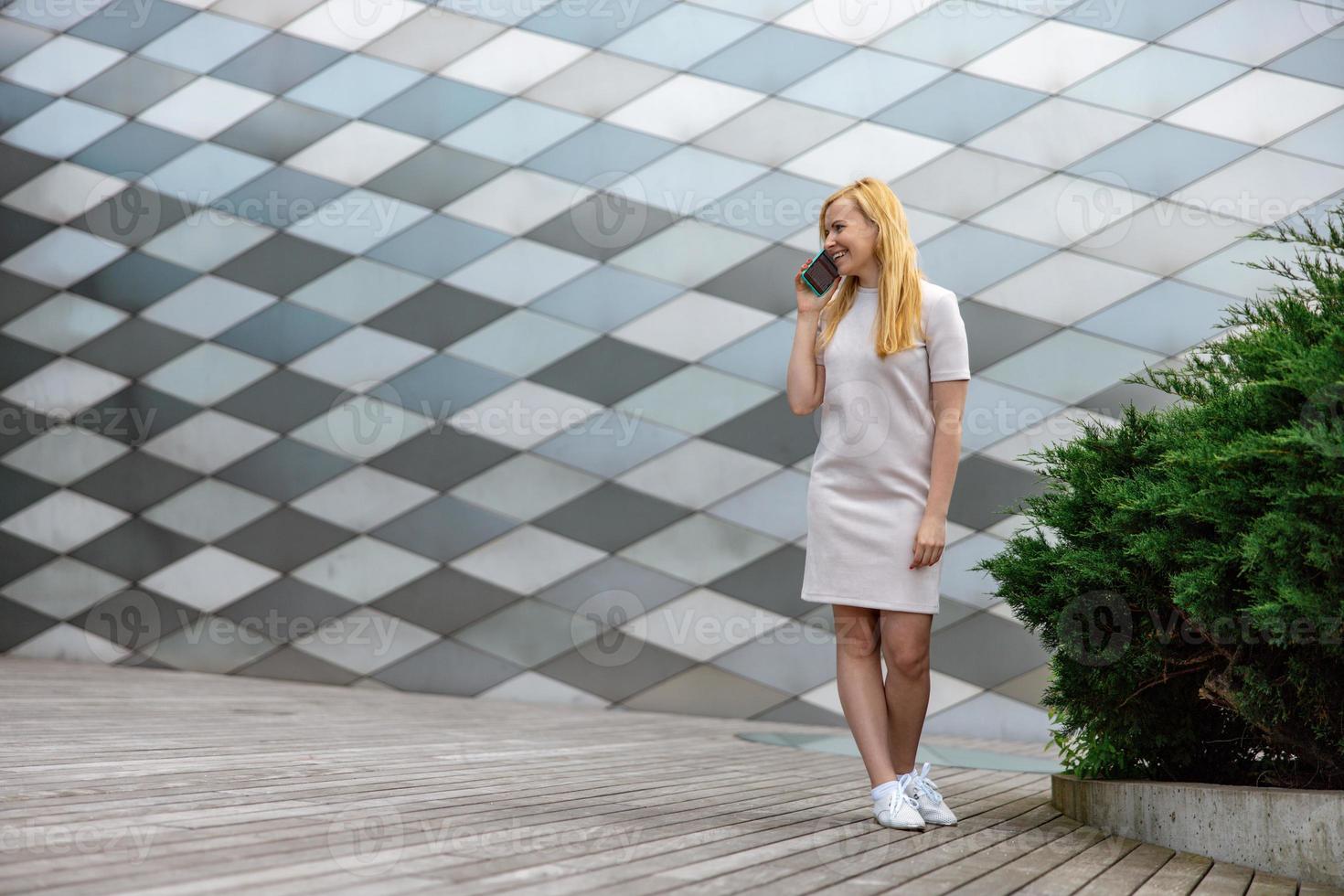 joven rubia haciendo una llamada con su teléfono inteligente. chica hablando con amigos con teléfono móvil. actividad de ocio, comunicación. conversación. tecnología móvil. foto