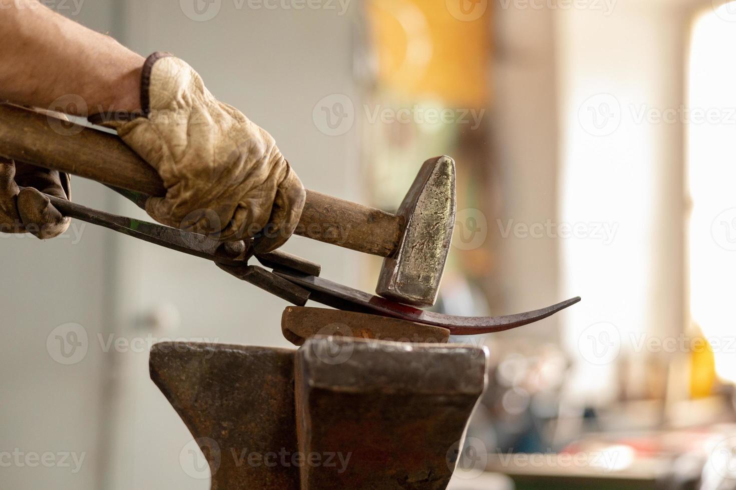 Close up view of heated metal and anvil. The blacksmith in the production process of metal products handmade in the forge. Blacksmith forging metal with a hammer. Metal industry, old profession. photo
