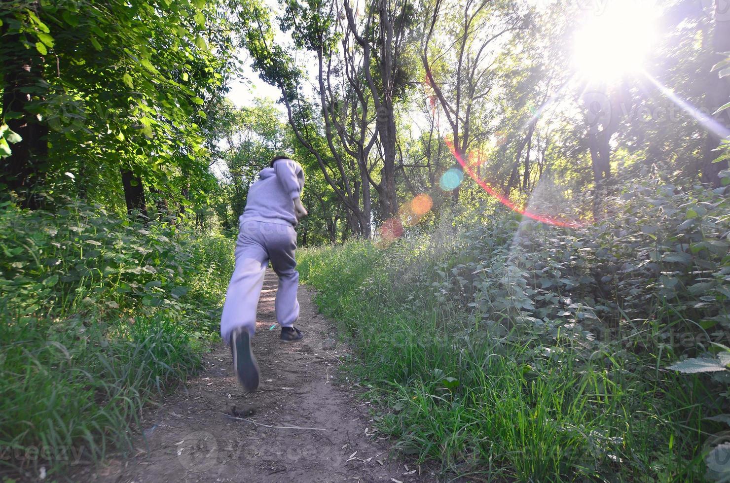 un joven con un traje deportivo gris corre por el camino entre los foto