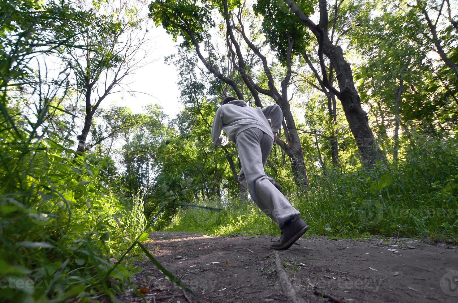 A young guy in a gray sports suit runs along the path among the photo