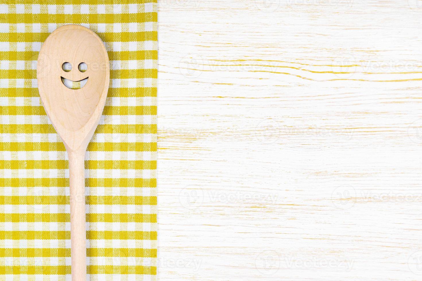 Kitchen mockup. Wooden spoon with smile on white wooden background. Food background with copy space photo