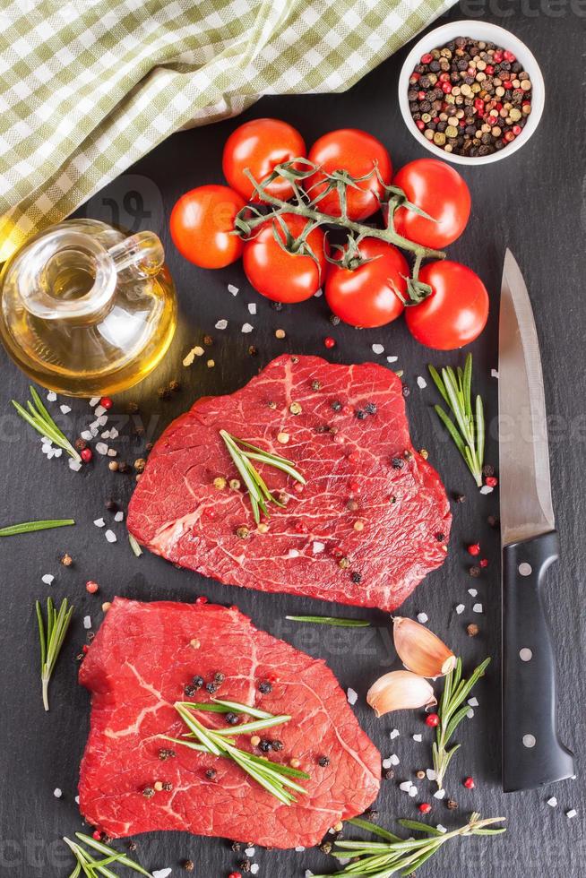 Fresh raw beef steak with spice on black background photo