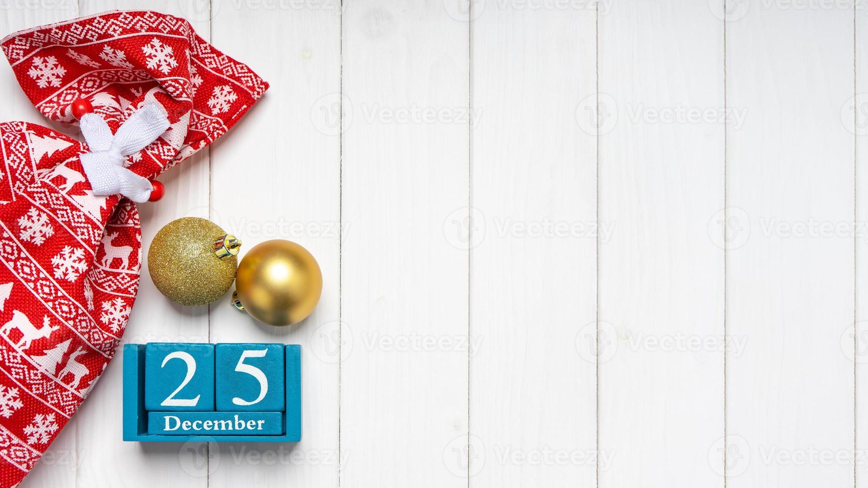 Cristmas background with red gift bag and perpetual wooden calendar on white wooden background. photo