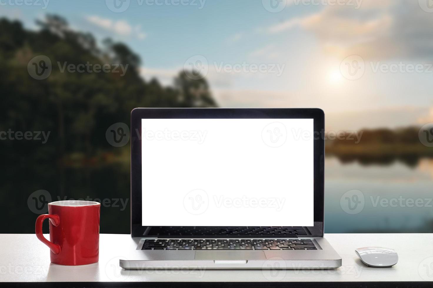 vista frontal de la taza y la computadora portátil en la mesa foto