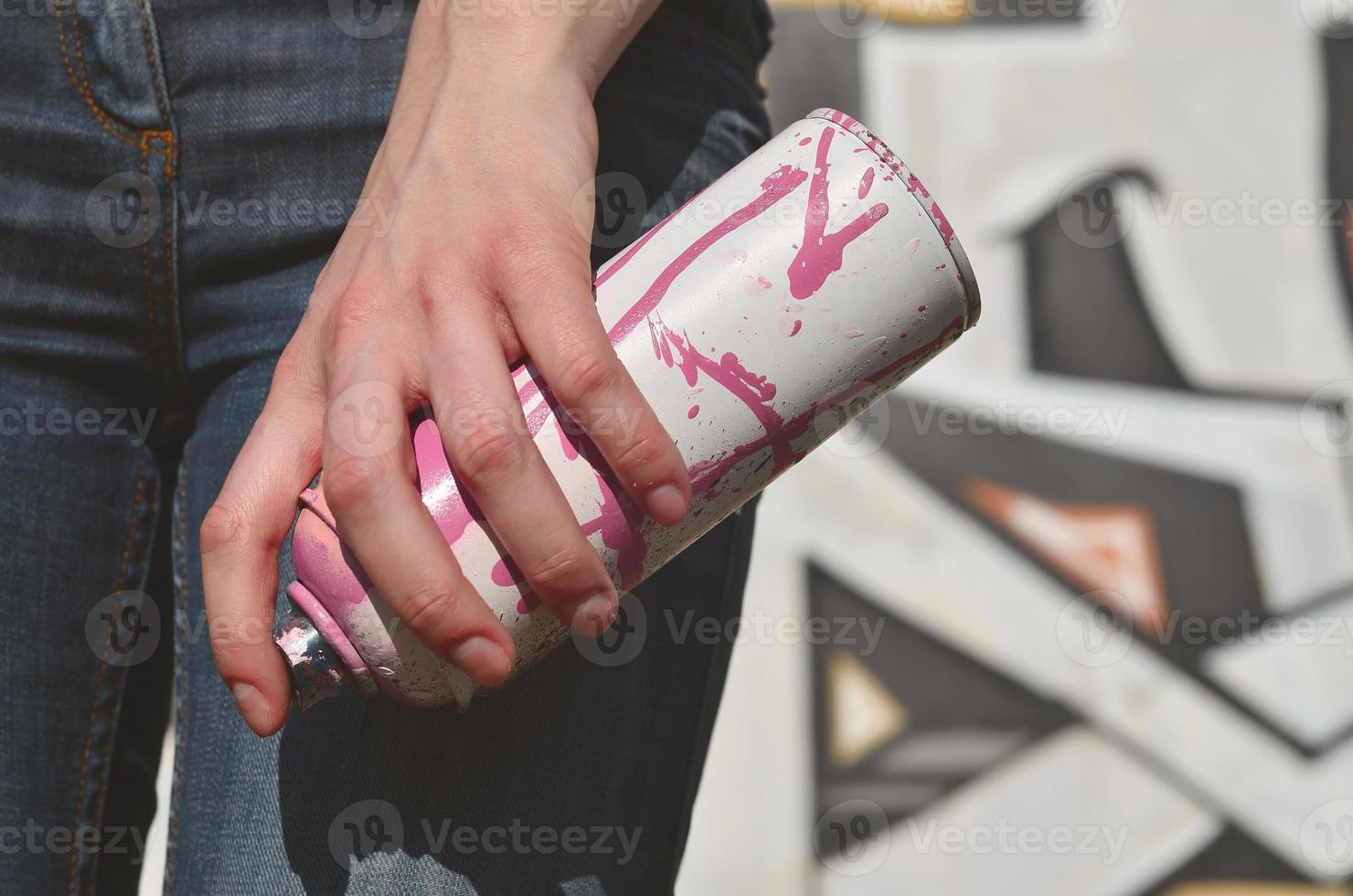 Photo of a girl's hand with aerosol paint cans in hands on a graffiti wall background. The concept of street art and use of aerosol paints. Graffiti art shop background image