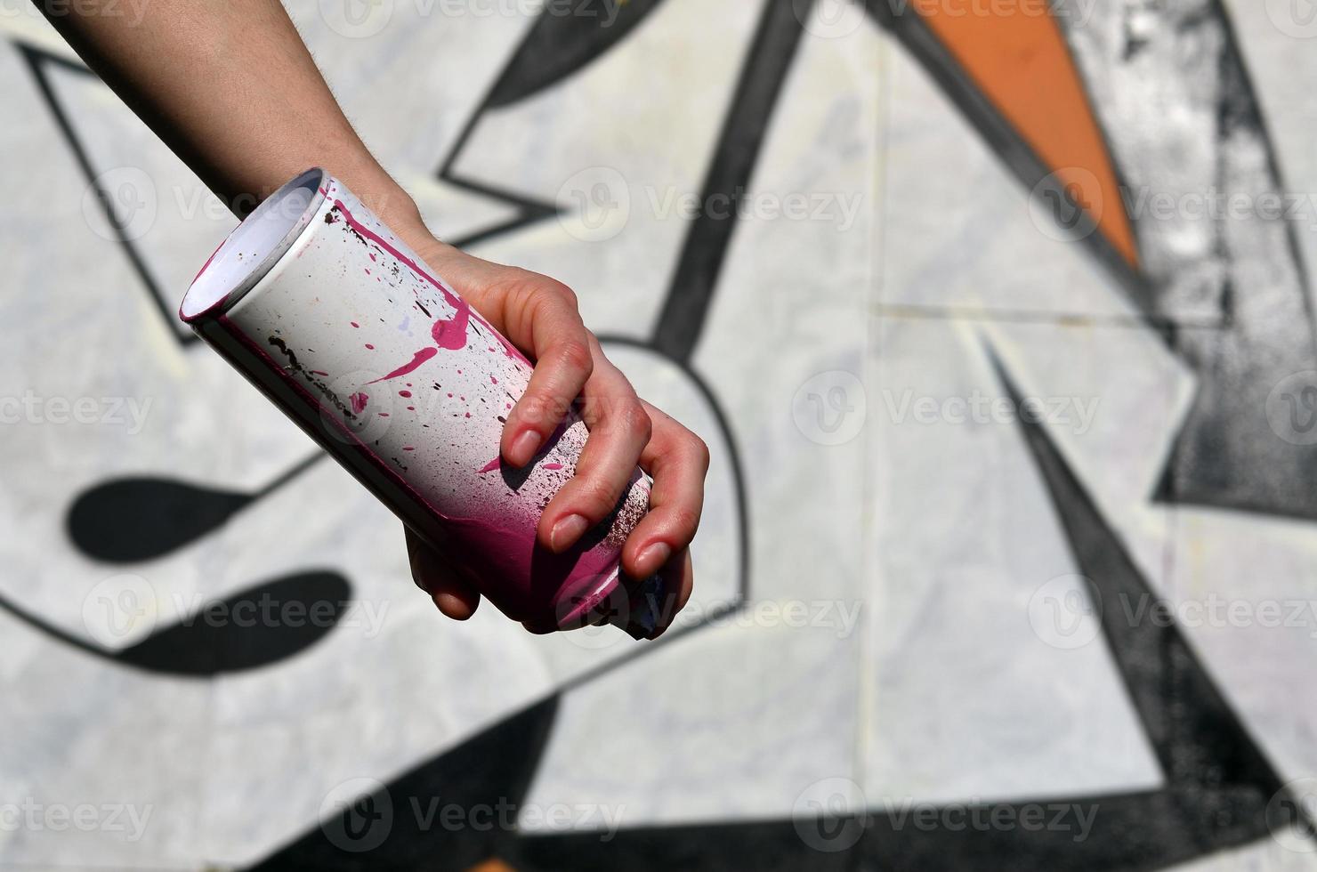 Photo of a girl's hand with aerosol paint cans in hands on a graffiti wall background. The concept of street art and use of aerosol paints. Graffiti art shop background image