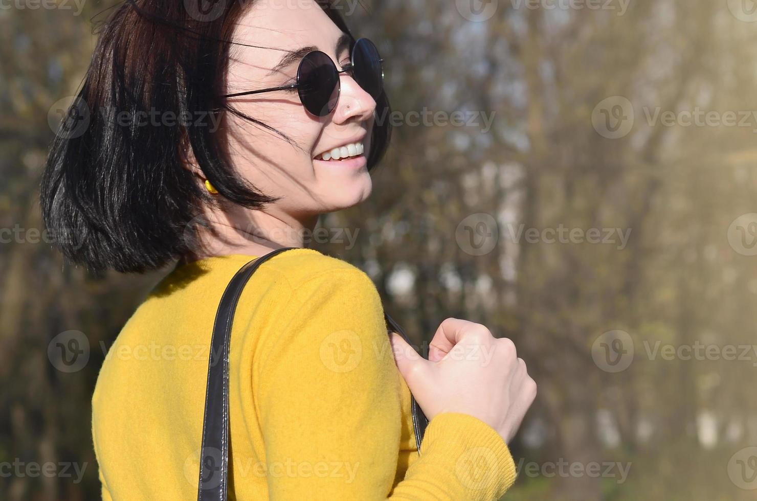 A joyful girl in a bright yellow sweater walks through the sprin photo