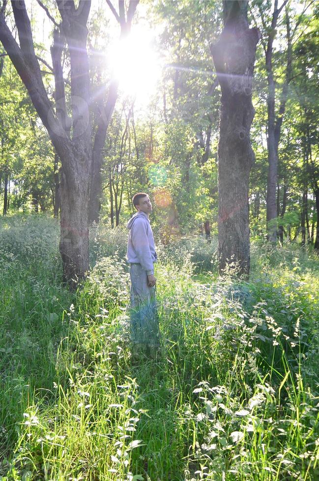 A young guy in a gray sports suit stands opposite the sun among photo