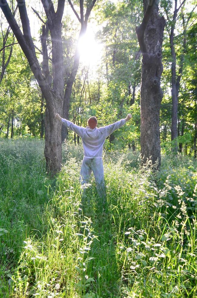 A young guy in a gray sports suit rejoices in the rising of the photo