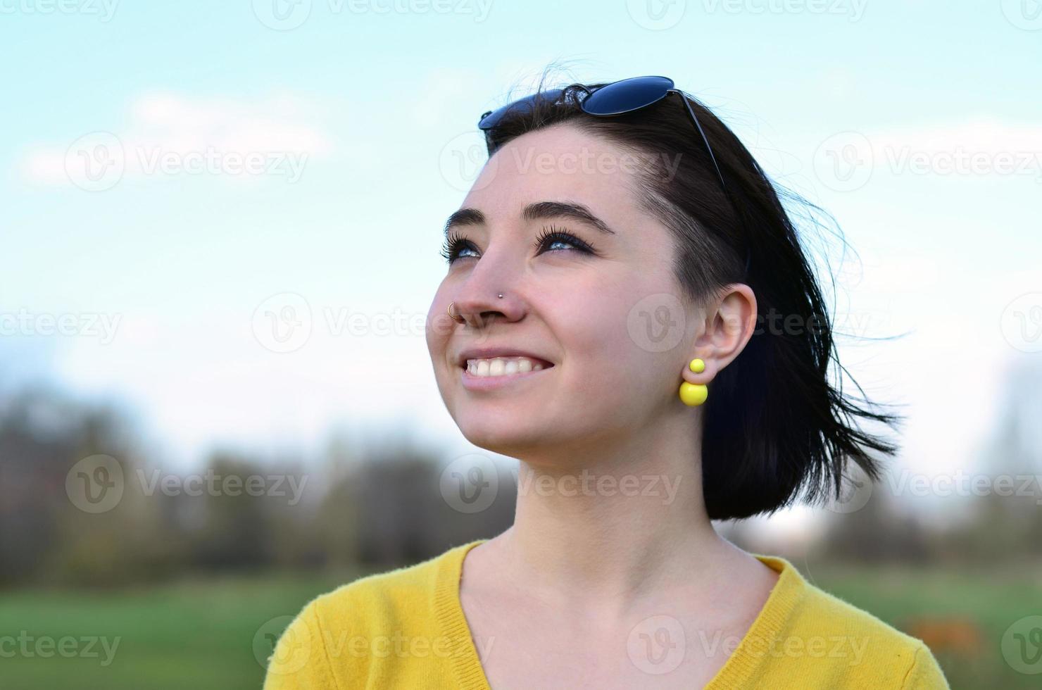 Attractive and cute Brunette girl in a yellow sweater against a photo