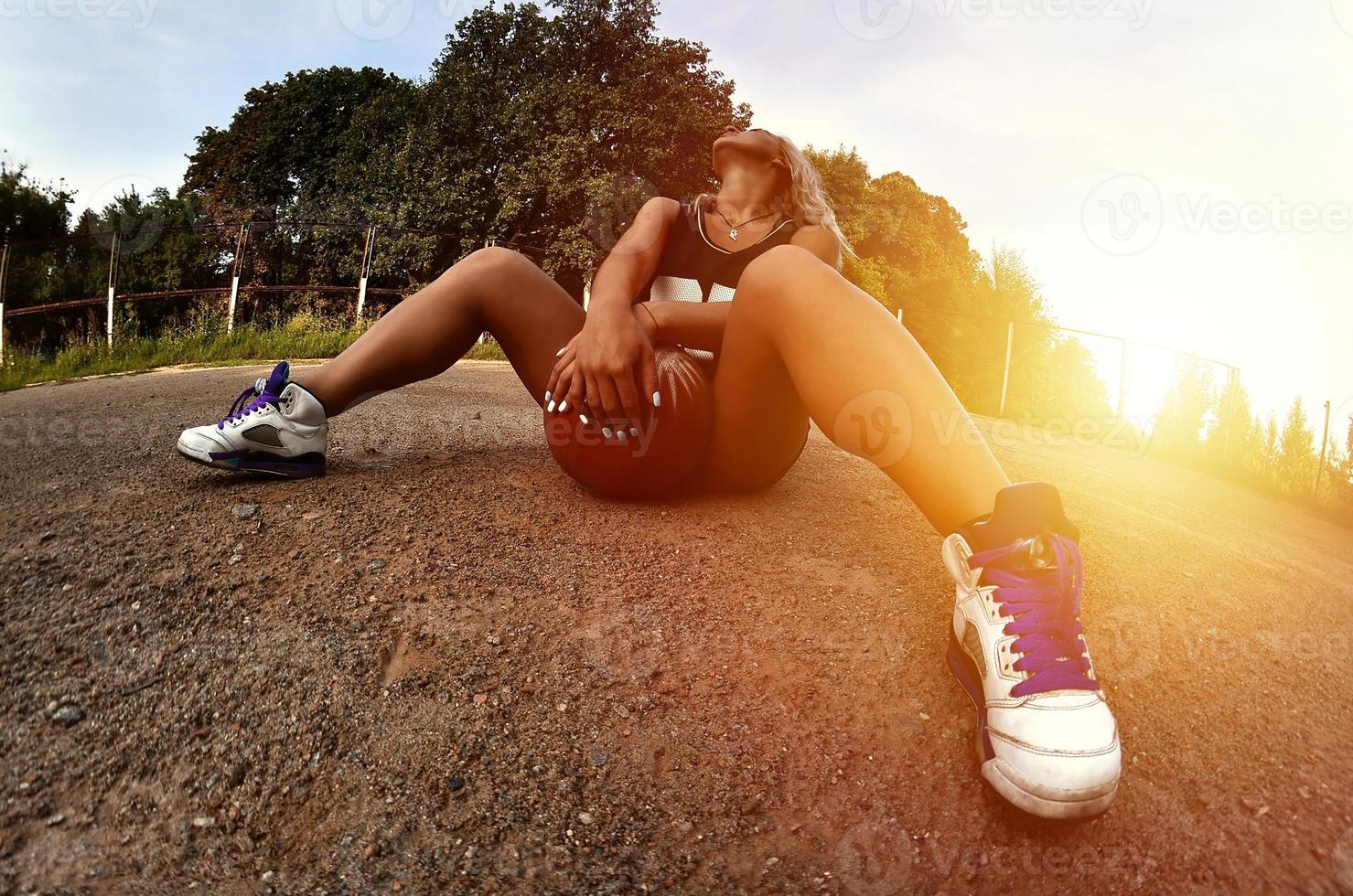 Young blonde girl with orange basketball posing outdoors photo