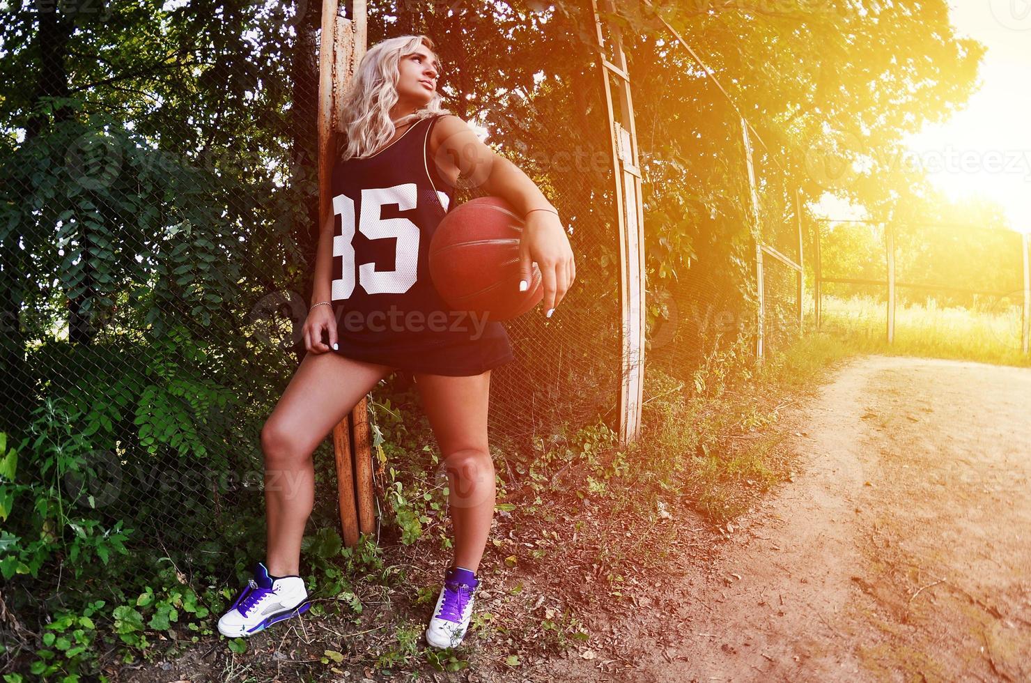 jovencita rubia con baloncesto naranja posando al aire libre foto