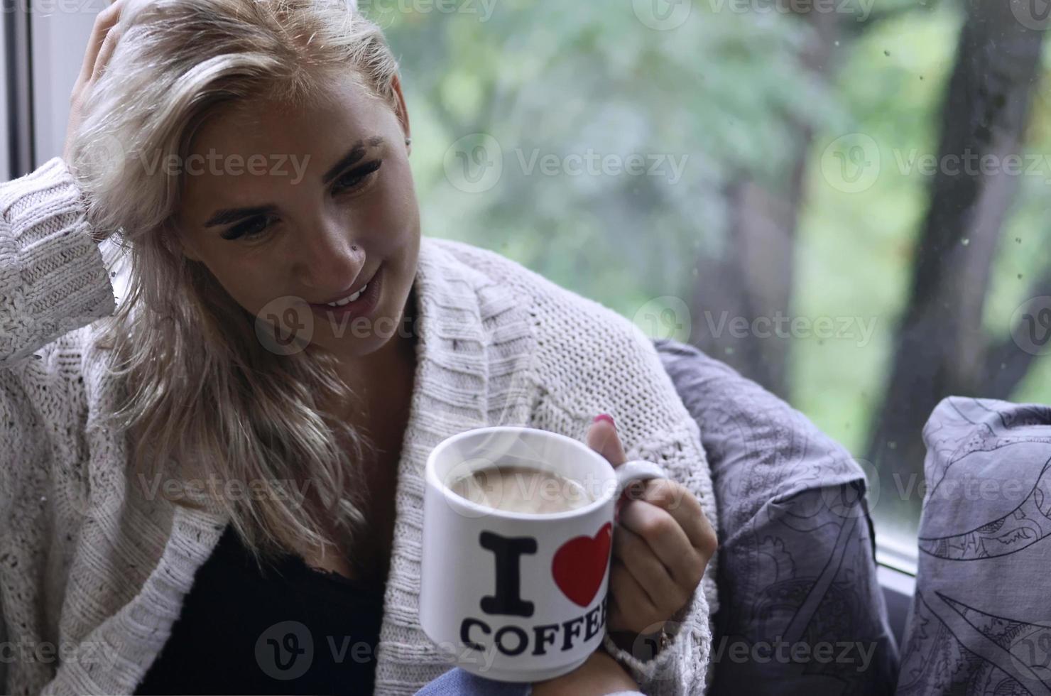 chica rubia en un suéter cálido con una taza de café sentada en un foto