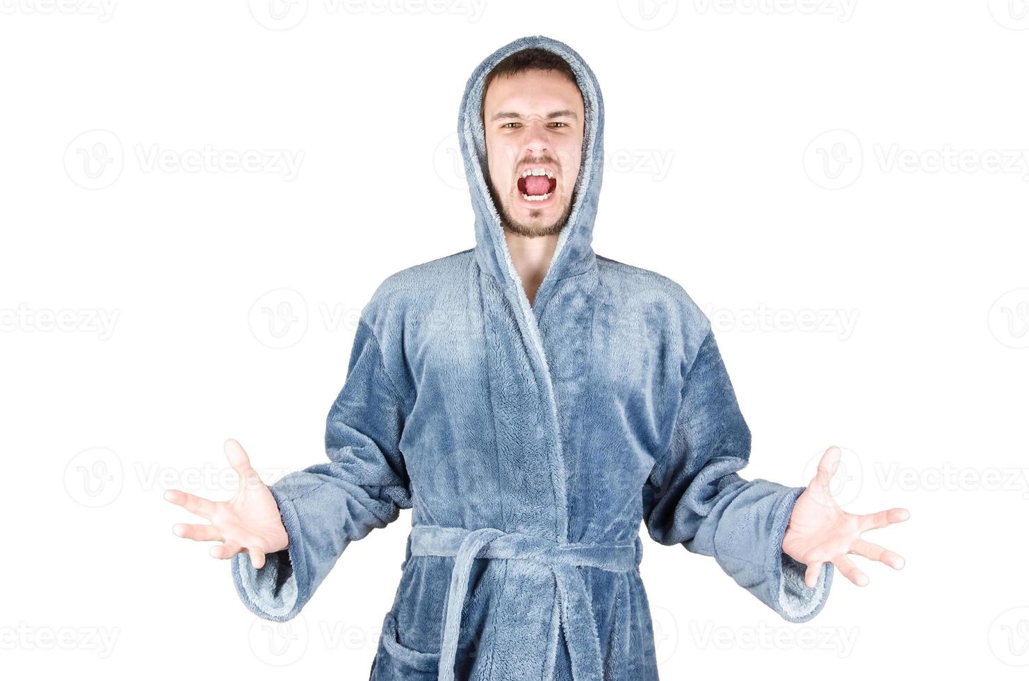 Portrait of young caucasian bearded man in blue bathrobe shouts in aggression isolated on white background photo