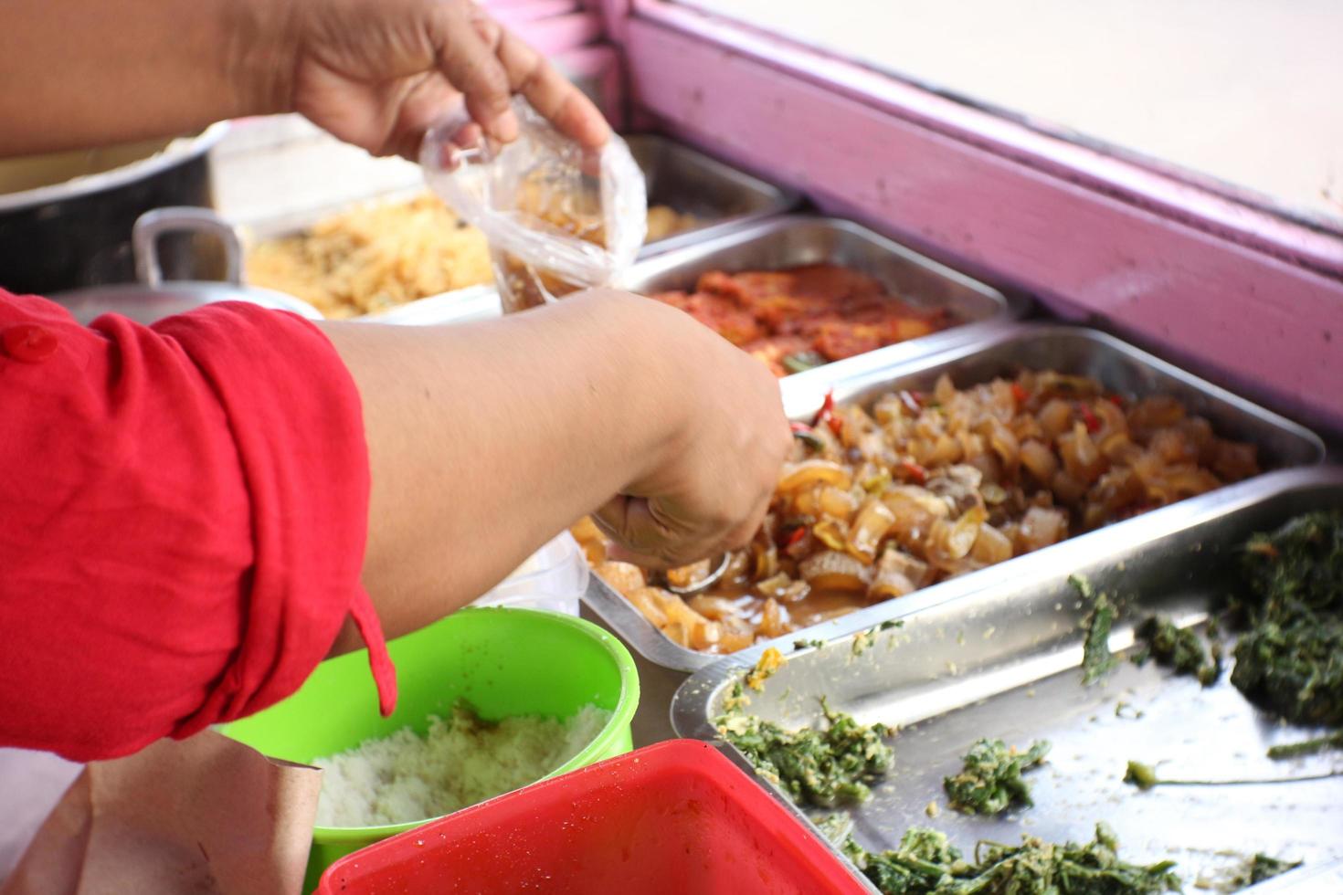 An old Indonesian woman is preparing vegetable  dishes for customers. photo