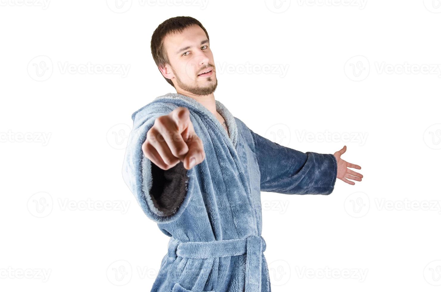 Portrait of young caucasian bearded man in blue bathrobe pointing finger to you gesture isolated on white background photo