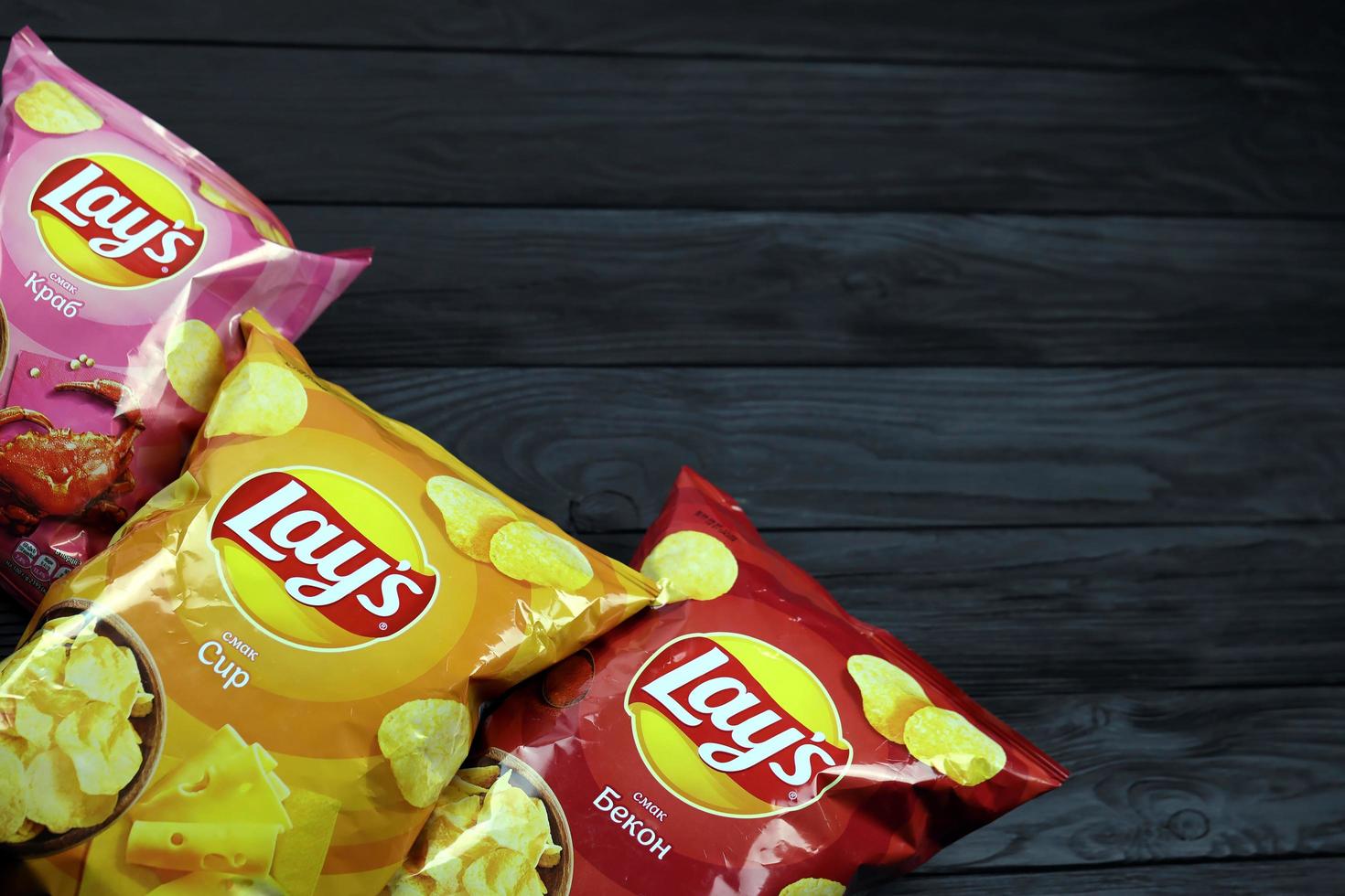 KHARKOV, UKRAINE - JANUARY 3, 2021 Various flavoured of lay's potato chips on wooden background. Lay's has been owned by PepsiCo through Frito-Lay in 1965 photo