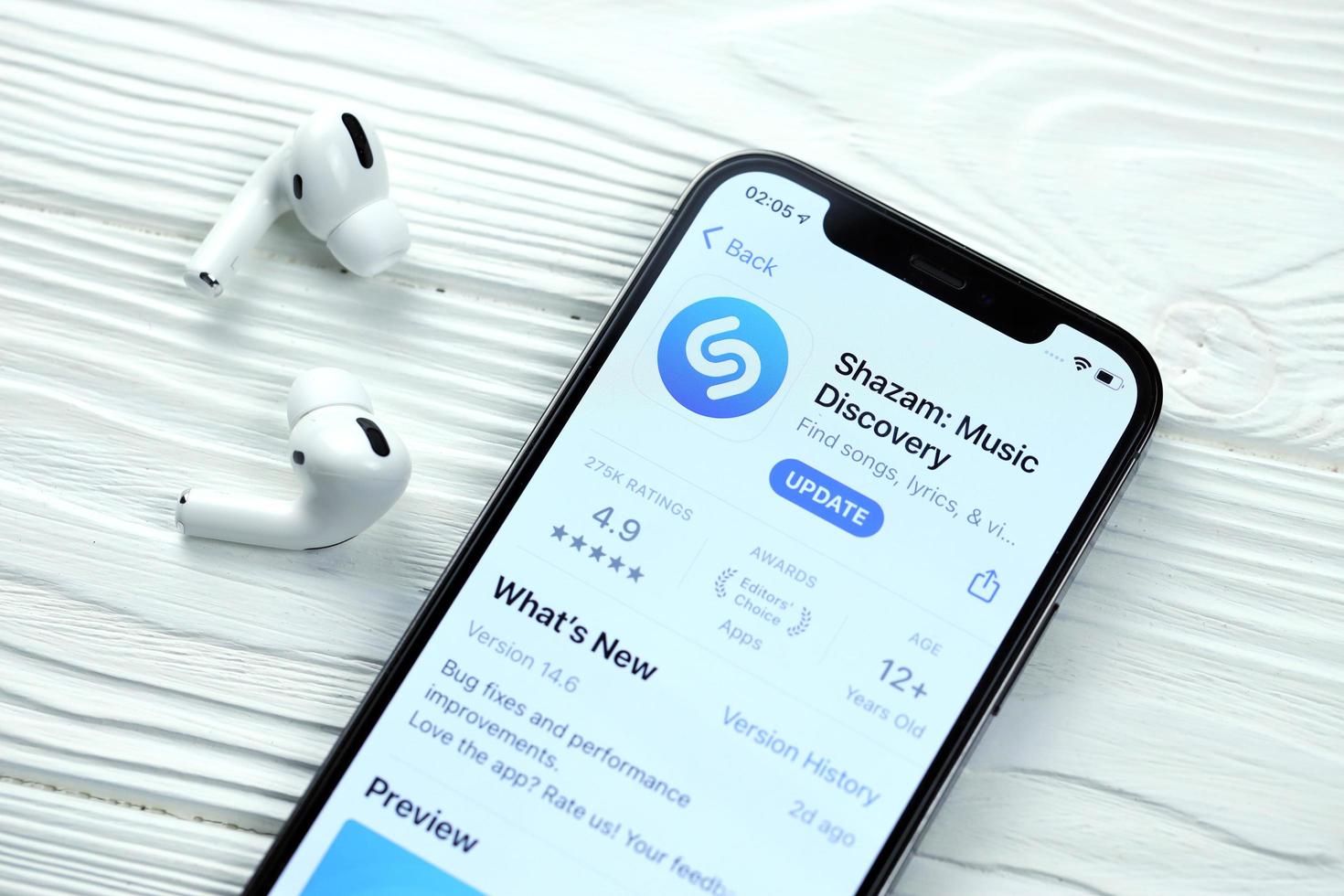 KHARKOV, UKRAINE - MARCH 5, 2021 Shazam icon and application from App store on iPhone 12 pro display screen with airpods pro on white table photo