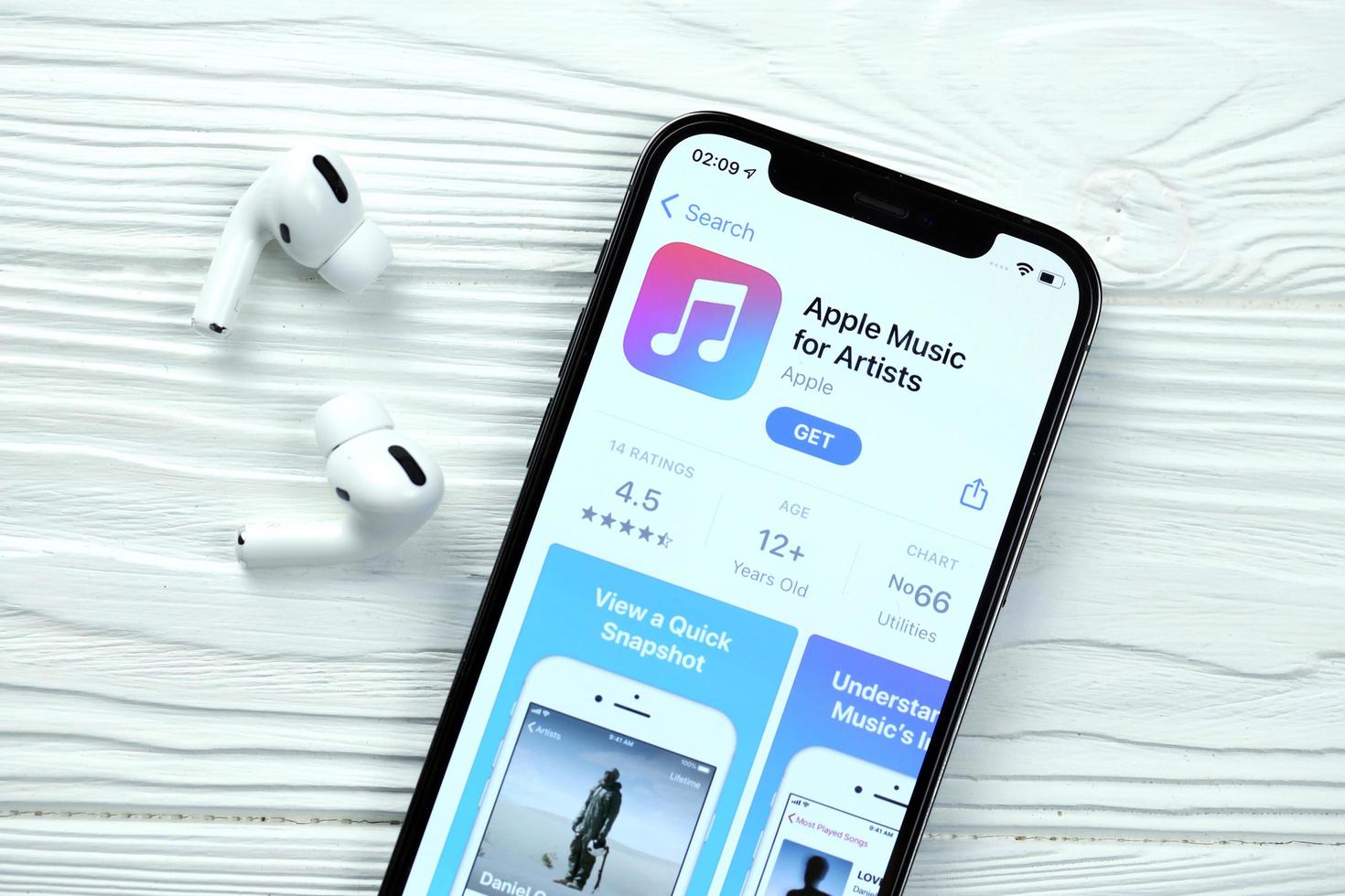 KHARKOV, UKRAINE - MARCH 5, 2021 Apple music for artists icon and application from App store on iPhone 12 pro display screen with airpods pro on white table photo